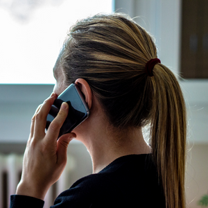 Woman on the phone looking out a window - calls for help are increasing